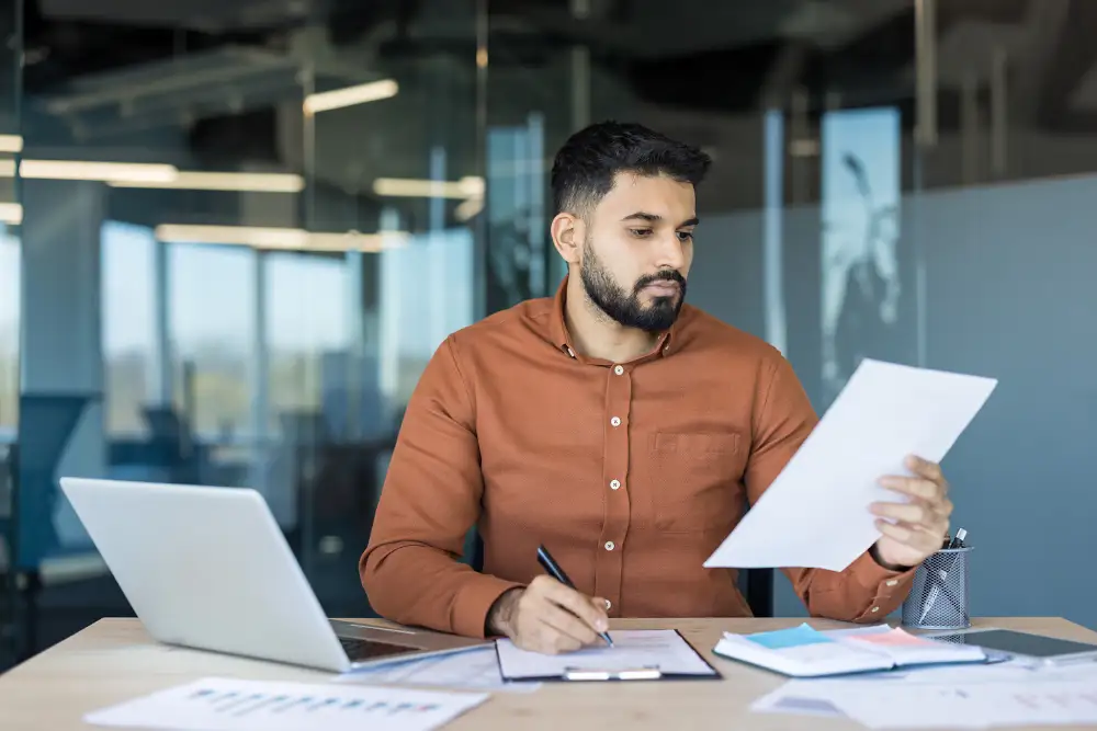 man at a desk looking at a piece of paper